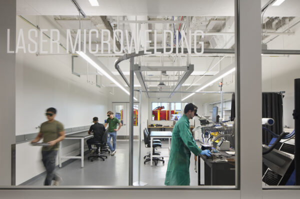 Interior view of the Missouri Protoplex laser micromachining lab with researchers working in a glass-enclosed advanced manufacturing space.